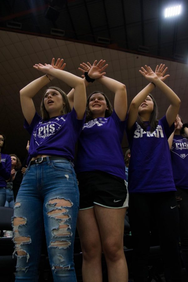 Seniors Bella Gravatt, Chloe Rogers, and Natalie Frick hold up spirit fingers silently as senior Christian Arndt makes a free throw in the fourth quarter of the Pirate v Buhler game on March 12. Frick has has cheered some of her friends on as they have  grown into athletes over the years. "Throughout the years I have become more involved in the student section because my friends are now playing for the teams that we cheer on," Frick said. "Watching the games now as an upperclassman means more because I am close to the people on the court."